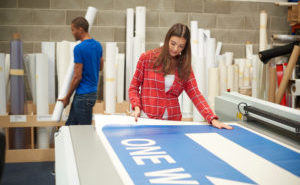 young woman working at a digital printing company A young woman printing a large sign.