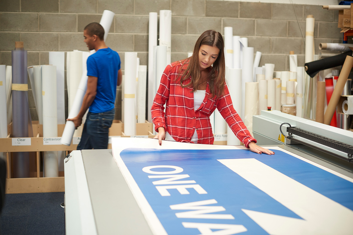 young woman working at a digital printing company A young woman printing a large sign.